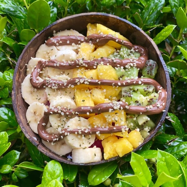 Big Island Bowls' healthy acai bowl with banana, pineapple, kiwi, chocolate drizzle, and hemp seeds.