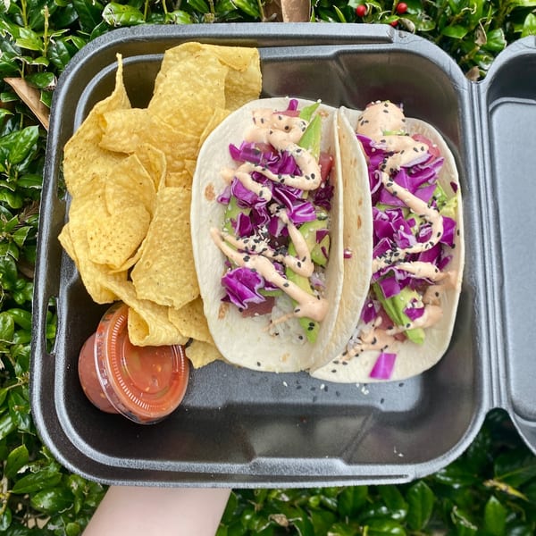 Two Big Island Bowls poke tacos with purple cabbage, avocado, sauce, and tortilla chips.