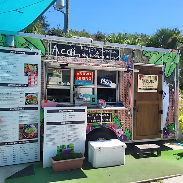 Big Island Bowls food truck with a menu, "Now Hiring" and "Open" signs, and tropical decor.