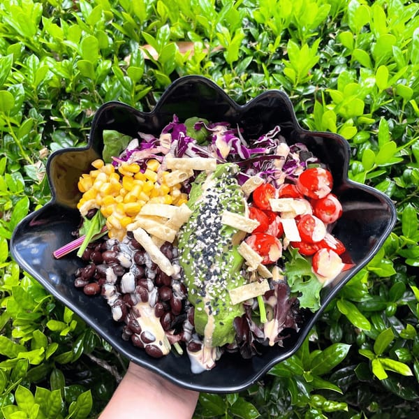 A Big Island Bowls salad with avocado, corn, black beans, tomatoes, and purple cabbage.